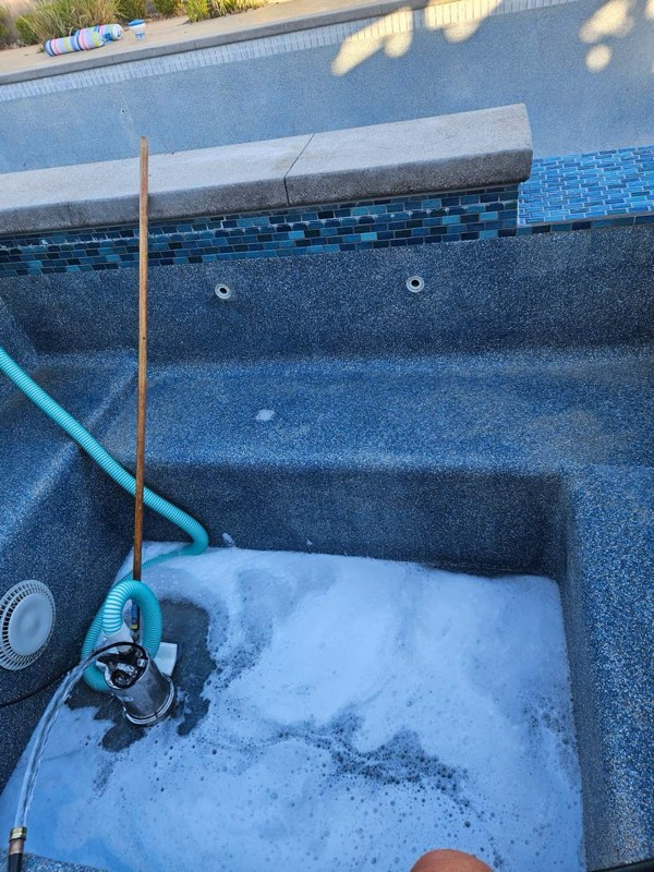 A drained pebble-finish pool during an acid and chlorine wash