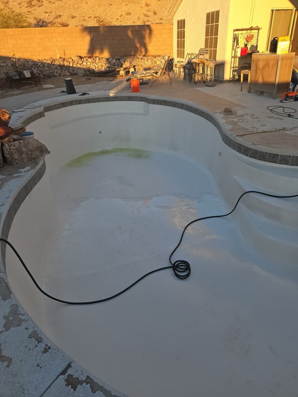 An empty fiberglass pool with the tile line cleaned, seen at sunset